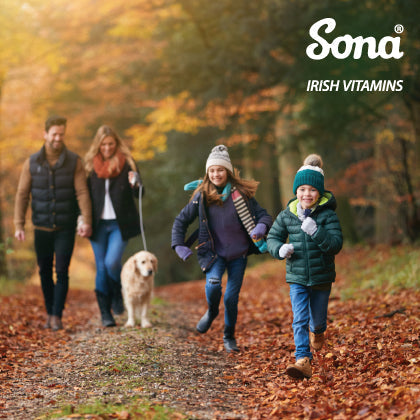 Family with kids and dog walking in autumn forest, representing health and wellness.