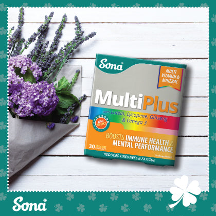 Sona MultiPlus multivitamin box placed next to lavender and purple flowers on a white wooden background. The packaging highlights benefits like boosting immune health and mental performance.